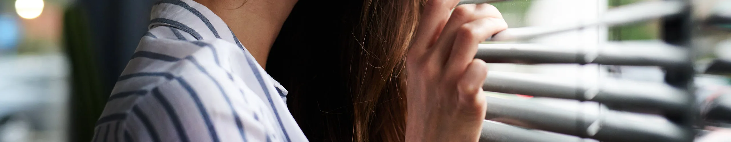 Kvinde der ser ud gennem persienner